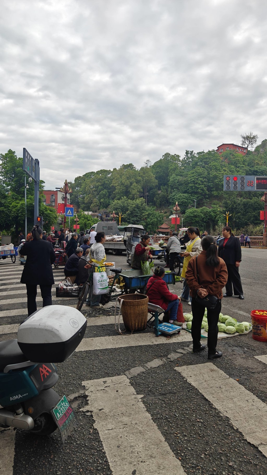 实拍马边老城本土赶集市井画面，依山而建的老城集市，是本地人日常赶场采购的老牌农贸市场。清晨农户背着竹篮、推着小车沿街摆摊，自种高山蔬菜、深山野生笋子、山间时令野果就地售卖，满是淳朴的山城烟火气。背靠满目青翠的山林，临街街巷摆满新鲜农家物产，所有食材都是山里农户当日现采现摘，没有中间商加价，也是马边各类山珍特产的原产地集散集市。来马边游玩必逛本地老街集市，在这里能淘到正宗马边竹笋、山野干货、彝乡农家土货，体验川西小县城原汁原味的赶场民俗。
