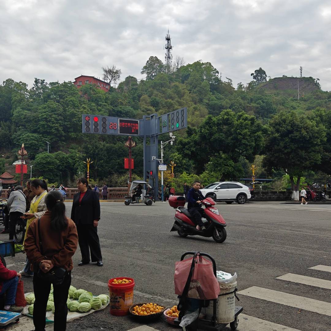 实拍马边老城本土赶集市井画面，依山而建的老城集市，是本地人日常赶场采购的老牌农贸市场。清晨农户背着竹篮、推着小车沿街摆摊，自种高山蔬菜、深山野生笋子、山间时令野果就地售卖，满是淳朴的山城烟火气。背靠满目青翠的山林，临街街巷摆满新鲜农家物产，所有食材都是山里农户当日现采现摘，没有中间商加价，也是马边各类山珍特产的原产地集散集市。来马边游玩必逛本地老街集市，在这里能淘到正宗马边竹笋、山野干货、彝乡农家土货，体验川西小县城原汁原味的赶场民俗。 class=