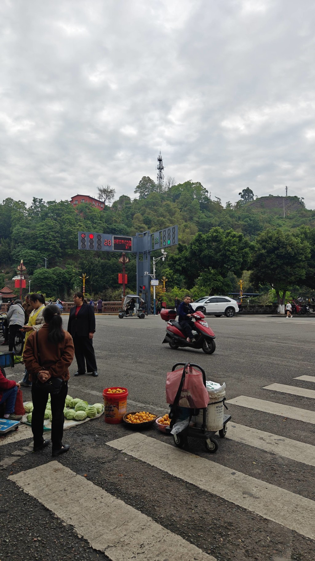 实拍马边老城本土赶集市井画面，依山而建的老城集市，是本地人日常赶场采购的老牌农贸市场。清晨农户背着竹篮、推着小车沿街摆摊，自种高山蔬菜、深山野生笋子、山间时令野果就地售卖，满是淳朴的山城烟火气。背靠满目青翠的山林，临街街巷摆满新鲜农家物产，所有食材都是山里农户当日现采现摘，没有中间商加价，也是马边各类山珍特产的原产地集散集市。来马边游玩必逛本地老街集市，在这里能淘到正宗马边竹笋、山野干货、彝乡农家土货，体验川西小县城原汁原味的赶场民俗。